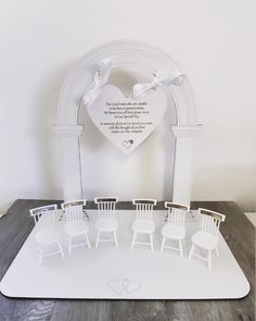 a white table topped with miniature chairs and a heart shaped frame on top of it