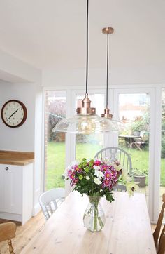 a vase with flowers sitting on top of a wooden table in front of a window