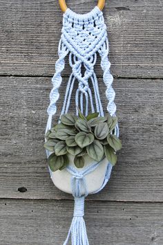 a macrame hanging from a wooden wall with plants in it and two handles