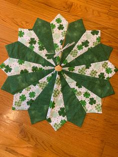 a green and white paper flower on top of a wooden floor