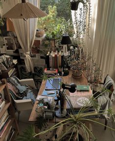 a room filled with lots of books and plants next to a laptop on a desk