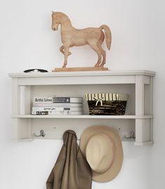 a hat and some books on a shelf with a horse figurine in the background