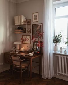 a room with a desk, chair and pictures on the wall next to a window