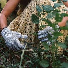 a woman kneeling down in the grass with gardening gloves on