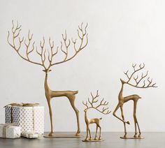 three gold deer figurines are standing next to a wrapped present