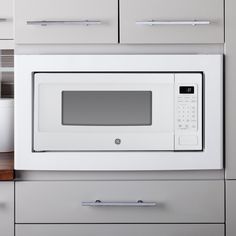 a white microwave oven sitting on top of a counter next to drawers and cupboards