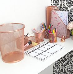 a desk with some pens, pencils and other office supplies on top of it