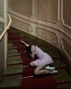 a woman kneeling down on top of a red carpeted stair case