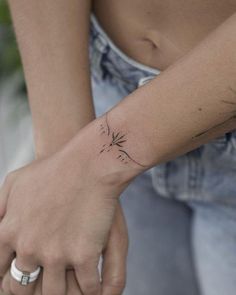 a woman's arm with a small tattoo on her left wrist, and a dandelion in the middle