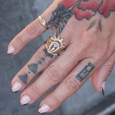 a woman's hand with tattoos and a ring on it