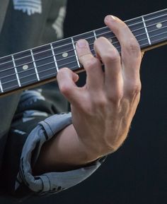 a close up of a person playing an electric guitar with their hand on the strings