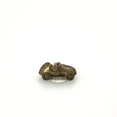 an antique silver car brooch sitting on a white surface with clippings to the side