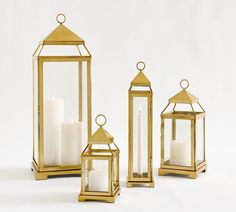 three gold lanterns with white candles in them