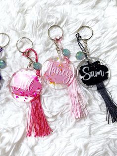 three personalized key chains with tassels on top of white furnishing