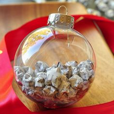 a glass ornament filled with snow flakes on top of a red ribbon