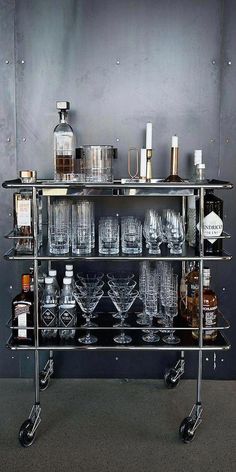 a metal bar cart filled with glasses and liquor bottles