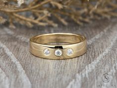 a gold wedding band with three diamonds on it