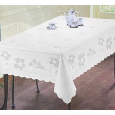 a white table cloth with flowers on it and two teapots next to it