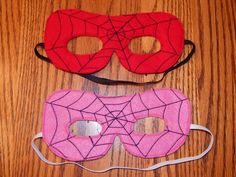 two pieces of pink and red cloth with spider webs on them sitting on a wooden table