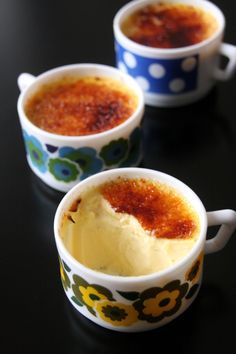 three cups filled with food sitting on top of a black table next to each other