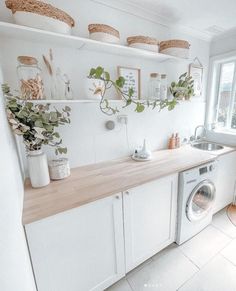 a washer and dryer in a small room with plants on the shelf above