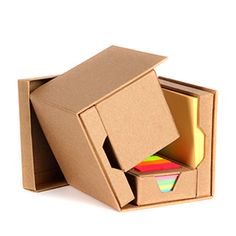 an open cardboard box with several different colored papers in it and the lid opened to reveal a multicolored piece of paper