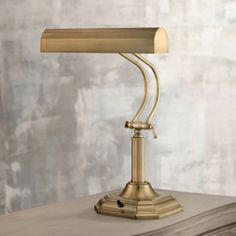 a gold desk lamp sitting on top of a wooden table