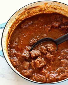 beef goulash in a blue pot with a black ladle on the side