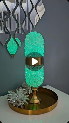 a green lamp sitting on top of a table next to a mirror and flower vase