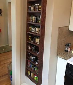 a tall wooden spice rack in the corner of a kitchen