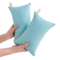 two blue pillows are being held by someone's hand