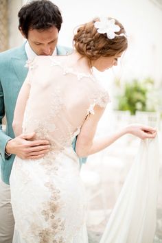 a man and woman in wedding clothes looking at each other's back while standing next to each other