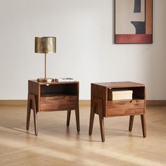 two wooden nightstands sitting on top of a hard wood floor next to a lamp