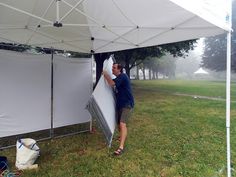 a man standing next to a white tent in the grass