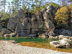 some rocks and water in the middle of a rocky area with trees on both sides