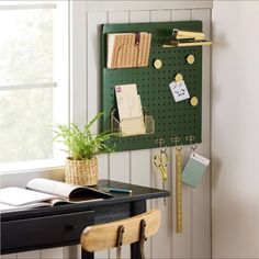 a green pegboard mounted to the side of a wall next to a desk with a potted plant