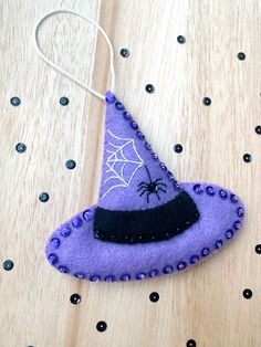 a purple witches hat ornament hanging from a string on top of a wooden table