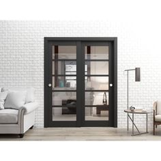 a living room with white brick walls and black glass doors