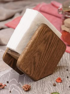 a wooden block with two napkins on it sitting on a table next to some nuts