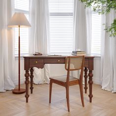 a wooden desk with a lamp and chair in front of white drapes on the windowsill