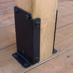 a close up of a speaker on a wooden floor with black metal brackets and screws