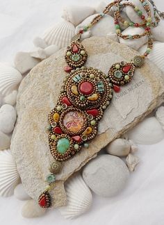 a close up of a necklace on a rock surrounded by shells and seashells