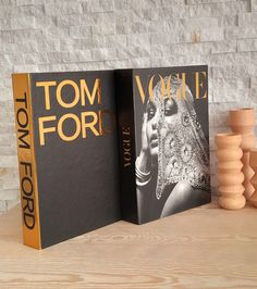 two books sitting on top of a table next to vases and a brick wall