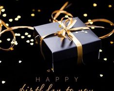 a black gift box with gold ribbon and confetti around it on a black background