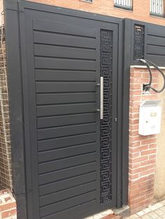 two black doors are open in front of a brick wall and telephone on the side