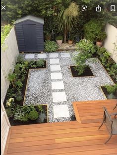 a small backyard garden with wooden decking and white stepping stones on the ground, surrounded by greenery