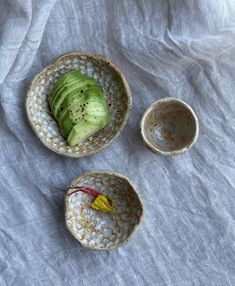 three bowls filled with food sitting on top of a white cloth covered table next to each other