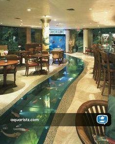 a restaurant with an aquarium in the center and tables on both sides, along with chairs