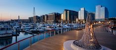 boats are docked in the harbor at dusk with city buildings in the backgroud