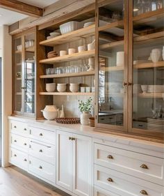 a kitchen with lots of white cabinets and dishes on top of it's shelves